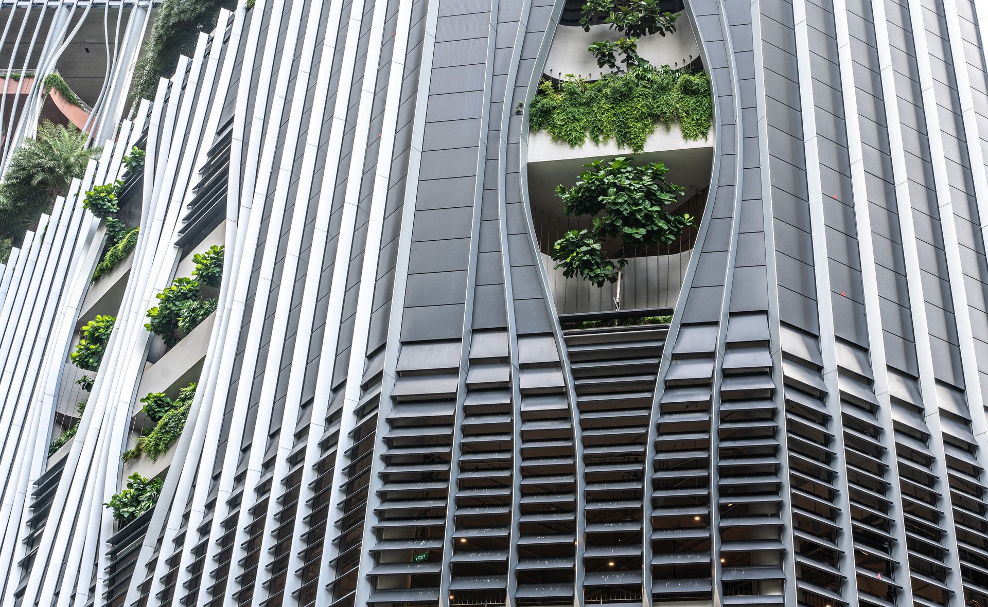 skyscraper in Singapore blends ultramodern design with lush greenery adorning facade, seamless integration of contemporary architecture and nature. urban sophistication and ecological beauty